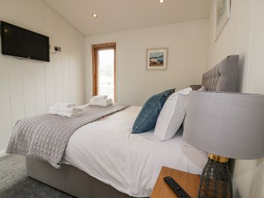 A bedroom with a bed a lamp and a wall mounted television at 9 Stonerush Valley in Lanreath