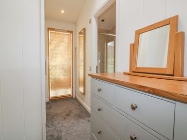 A hallway with a gray chest of drawers and a wooden framed mirror at 9 Stonerush Valley in Lanreath