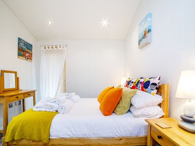 A bedroom with a wooden bed and side table with lamp at 2 Water's Edge in Lanreath
