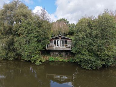 A wooden cabin on the edge of a river at 2 Water's Edge in Lanreath