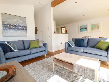 A living room with two blue sofas and a wooden coffee table at 4 Water's Edge in Lanreath