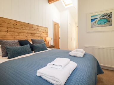 A bedroom with a bed covered in blue bedding and white towels on top at 4 Water's Edge in Lanreath