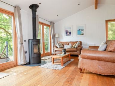 A living room with brown leather sofas a black wood stove and wooden coffee table at 6 Water's Edge in Lanreath