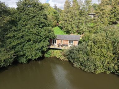 A cabin near a river with trees surrounding it at 6 Water's Edge in Lanreath
