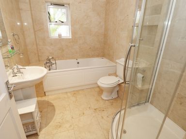 A bathroom with a bathtub a toilet a shower and a sink at The Sandcastle in Freshwater East