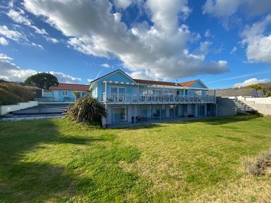 A two story house with a large lawn and covered swimming pool at The Sandcastle in Freshwater East
