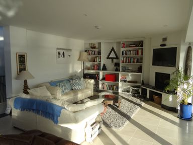 A living room with sofas cushions bookshelf and a television at The Sandcastle in Freshwater East