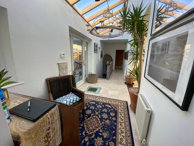 A hallway with a glass ceiling a chair and plants at The Sandcastle in Freshwater East