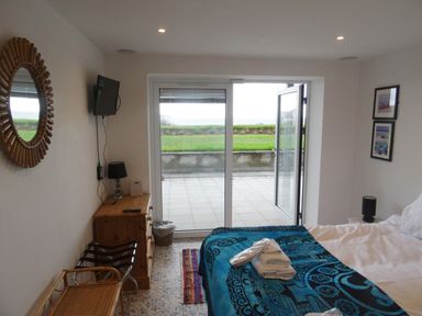 A bedroom with a bed and blankets next to glass doors opening to a patio and garden at The Sandcastle in Freshwater East