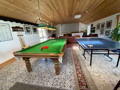 A game room with a snooker table and a ping pong table with sofas in the background at The Sandcastle in Freshwater East