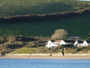 A house with a garden on a hill near a beach with water and green fields in the background at The Sandcastle in Freshwater East