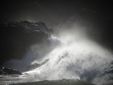 Waves crashing against rocks with water spray in a coastal scene at The Sandcastle in Freshwater East