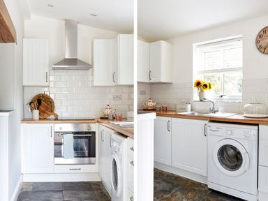A kitchen with white cabinets wooden countertops a stainless steel oven washing machine and a window with sunflowers at Lilly Cottage in Whitecroft Royal Forest of Dean