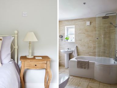 A bedroom with a nightstand and lamp next to a bathroom with a bathtub shower and sink at Lilly Cottage in Whitecroft Royal Forest of Dean