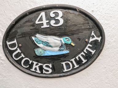 A black oval house sign with number 43 and a duck illustration with the text ducks ditty in Liskeard