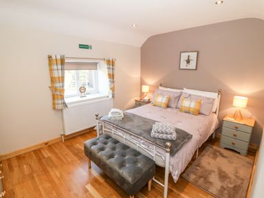 A bedroom with a double bed bedside tables lamps and a window with curtains at Min-y-rhos in Edern
