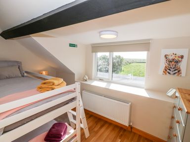 A bedroom with a bunk bed towels window with a view and a chest of drawers at Min-y-rhos in Edern