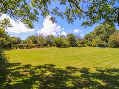 A large grassy garden with trees and a soccer goal at Sunbury Barn in St Agnes