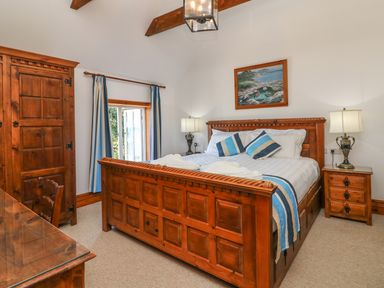 A bedroom with wooden bed frame, matching wardrobe and bedside tables with lamps at C S Lewis Balcony in Lynton