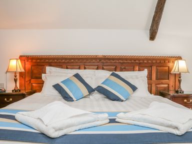 A bed with a wooden headboard two striped pillows two lamps and white towels at C S Lewis Balcony in Lynton