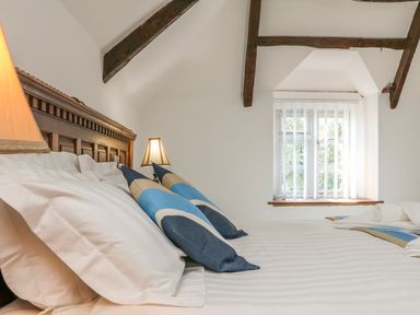 A bedroom with a wooden headboard bed pillows and cushions and a window with vertical blinds at C S Lewis Balcony in Lynton