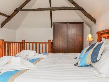 A bedroom with a bed with folded towels pillows a wooden wardrobe and exposed wooden ceiling beams at C S Lewis Balcony in Lynton