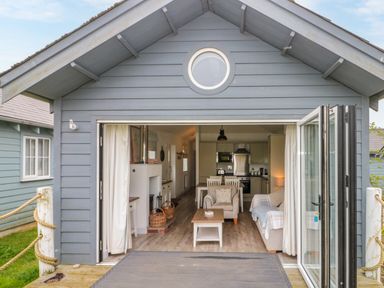 A small cabin with folding glass doors open to a living area with chairs a table and a kitchen at Sea Breeze in The Bay near Filey