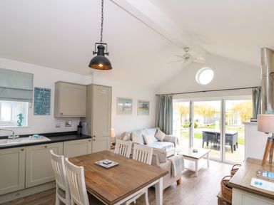 A kitchen and living room area with a wooden dining table and chairs near sliding glass doors at Sea Breeze The Bay near Filey