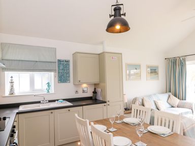 A kitchen and dining area with a wooden table set for four and a sofa with striped covers at Sea Breeze The Bay near Filey