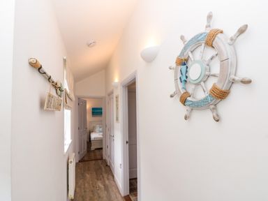 A hallway with wooden floor and white walls nautical decor and doors leading to a bedroom at Sea Breeze The Bay near Filey