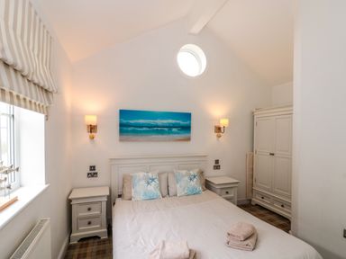 A bedroom with a double bed two bedside tables a wardrobe and a window with striped blinds at Sea Breeze The Bay near Filey
