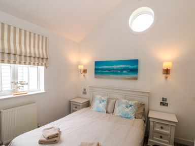 A bedroom with a double bed two bedside tables and a window with striped blinds at Sea Breeze The Bay near Filey