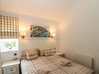 A bedroom with a double bed two bedside tables lamps and a window with checkered blinds at Sea Breeze The Bay near Filey