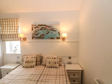 A bedroom with a double bed two bedside tables wall lamps and a painting at Sea Breeze The Bay near Filey