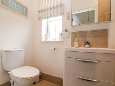 A bathroom with a toilet sink vanity window with striped blind and coast wall sign at Sea Breeze The Bay near Filey