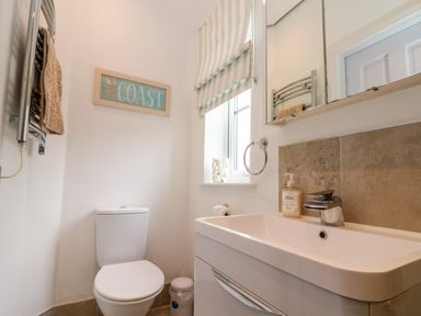 A bathroom with a toilet sink mirror towel rack and window at Sea Breeze in The Bay near Filey