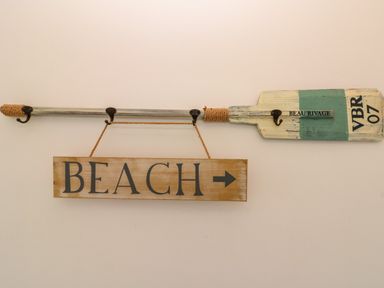 A wooden paddle mounted on a wall with a hanging sign that says beach with an arrow at Sea Breeze The Bay near Filey