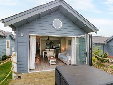 An open living room and kitchen inside a small blue wooden house with a dining table sofa coffee table and outdoor table at Sea Breeze The Bay near Filey