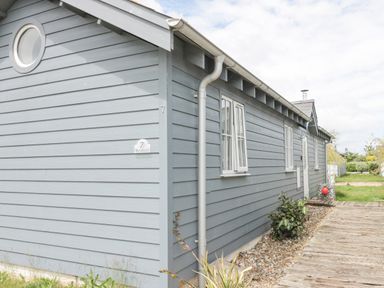 Exterior view of a gray wooden building with white-trimmed windows and a small garden path at Sea Breeze The Bay near Filey