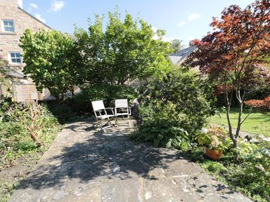 A garden patio with two chairs and fruit trees at Teviot Cottage in Corbridge