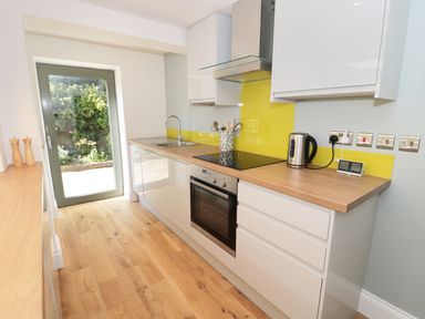 A kitchen with wooden countertops cabinets an oven a sink a kettle and a glass door at Teviot Cottage in Corbridge