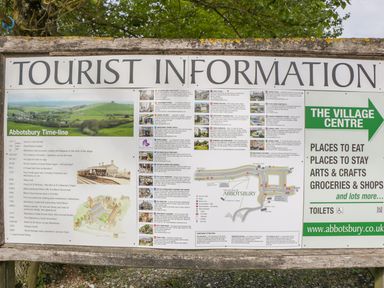 A tourist information board with a village timeline map and local place details at Abbotsbury