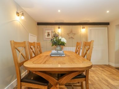A wooden dining table with six chairs and a flower vase in the center in a dining room at Market House in Abbotsbury