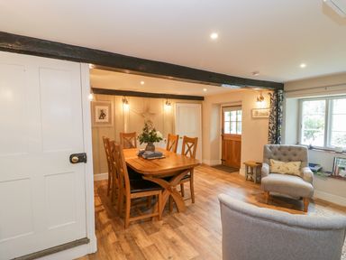 A dining area with wooden table and chairs and a sitting area with armchairs and a window at Market House in Abbotsbury