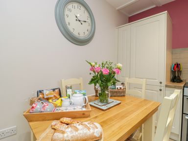 A kitchen with a wooden table set with bread flowers and tea items at Market House in Abbotsbury