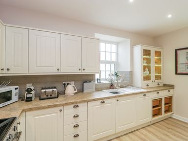 A kitchen with white cabinets countertop appliances and a window at Market House in Abbotsbury