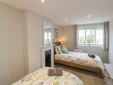 A bedroom with two single beds a window and a fireplace at Market House in Abbotsbury