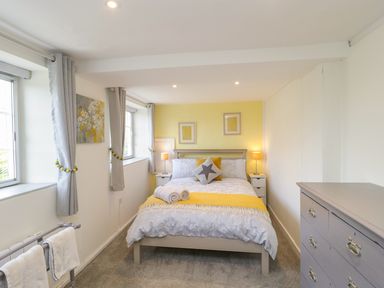 A bedroom with a bed table lamps and a chest of drawers at Market House in Abbotsbury