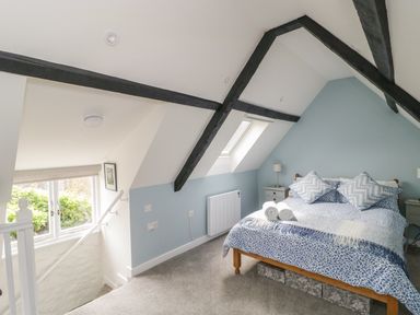 A bedroom with a bed, side tables, and stairs by a window at Market House in Abbotsbury