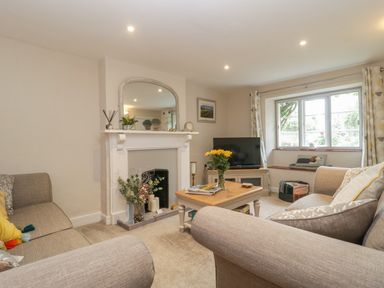 A living room with sofas a coffee table and a fireplace with a mirror above at Market House in Abbotsbury